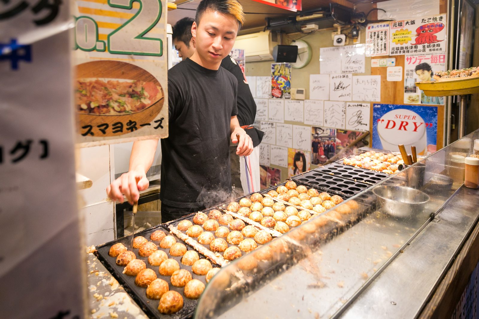 Takoyaki being turned on a hot iron griddle