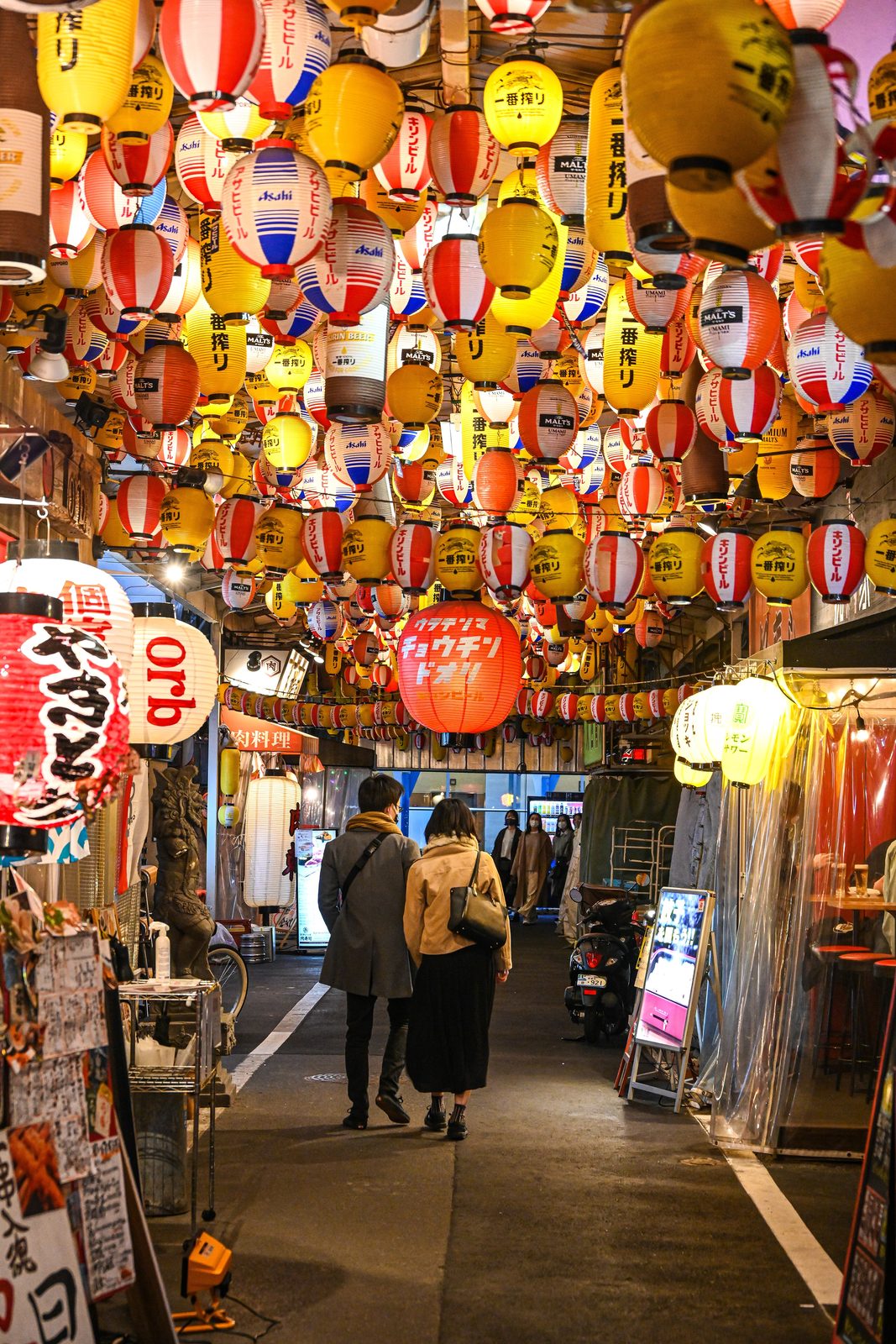 Red lanterns over a night-time izakaya alley in Osaka